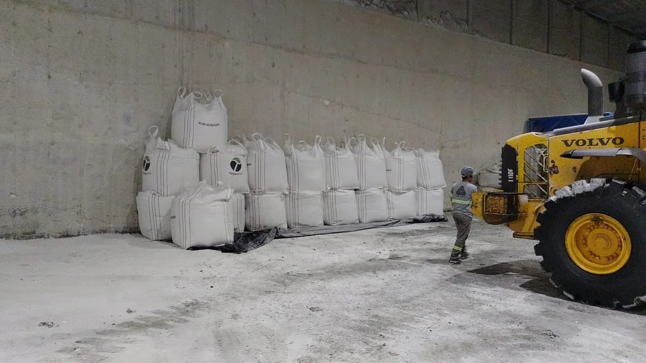 Big bags empilhados no armazém e pá carregadeira em operação